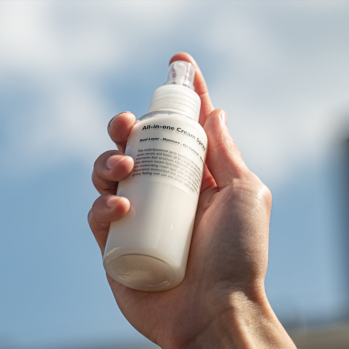 LAZY SOCIETY All-in-One Cream Spray 120ml held by hand against sky, Gentleman Korea men’s skincare product for gentlemen