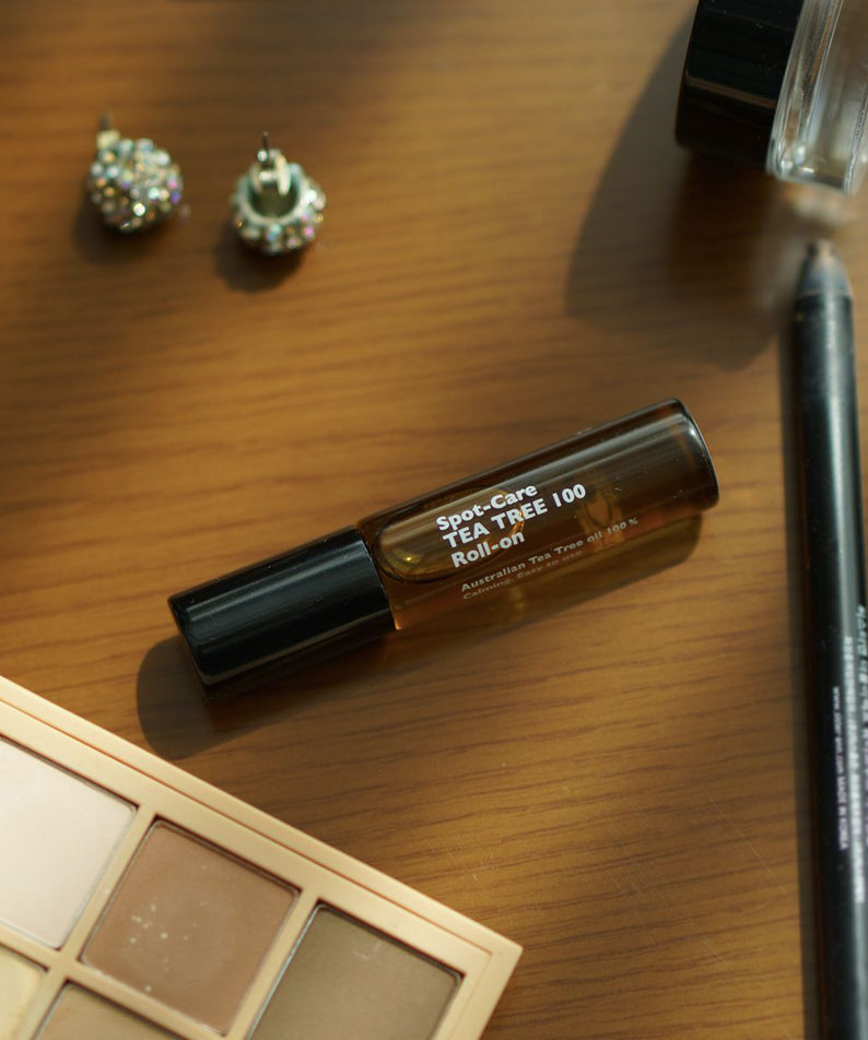 LAZY SOCIETY Spot Care Tea Tree 100 Roll on 5.5ml placed on wooden table with makeup items, Gentleman Korea export for men’s skincare