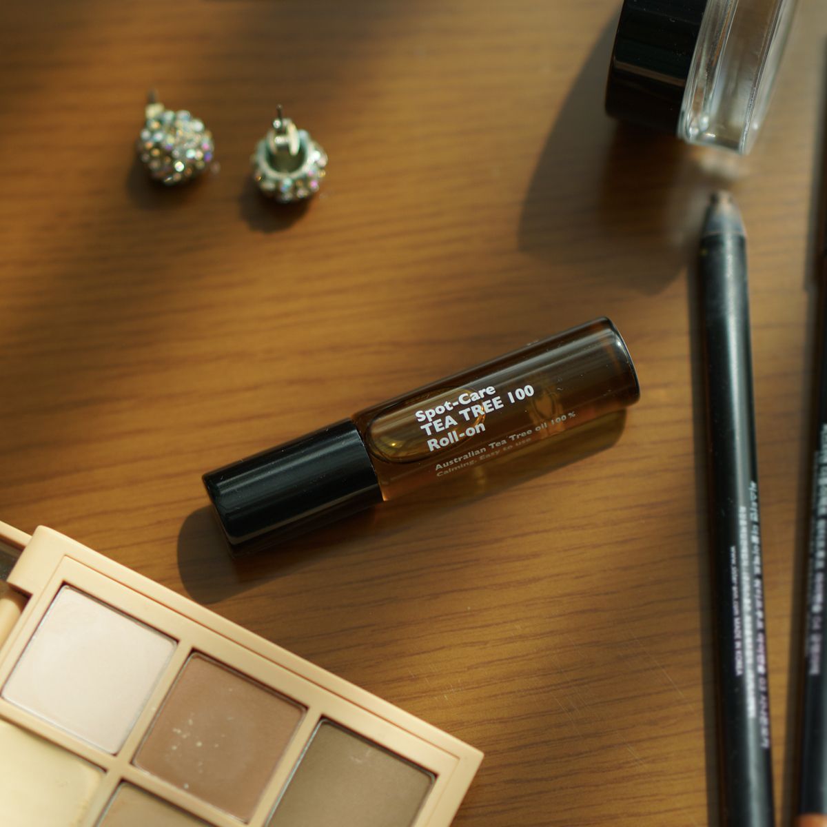 LAZY SOCIETY Spot Care Tea Tree 100 Roll on 5.5ml placed on wooden table with makeup items, Gentleman Korea export for men’s skincare
