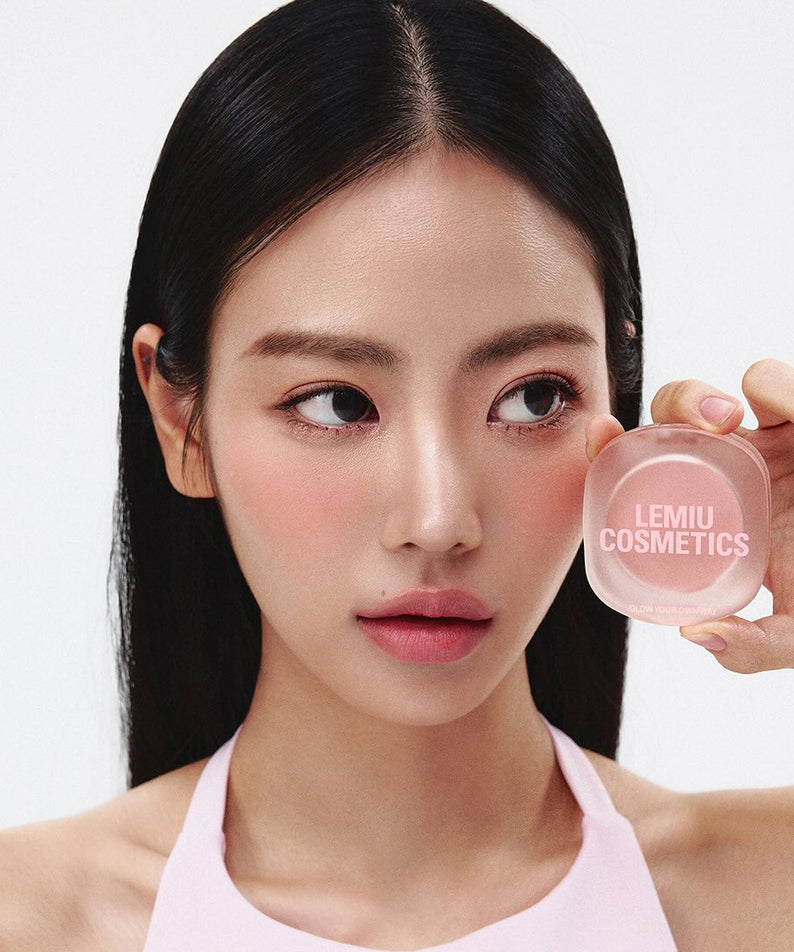 Woman holding LEMIU Eye To Cheek product near her face, showcasing its use for eye and cheek beauty.
