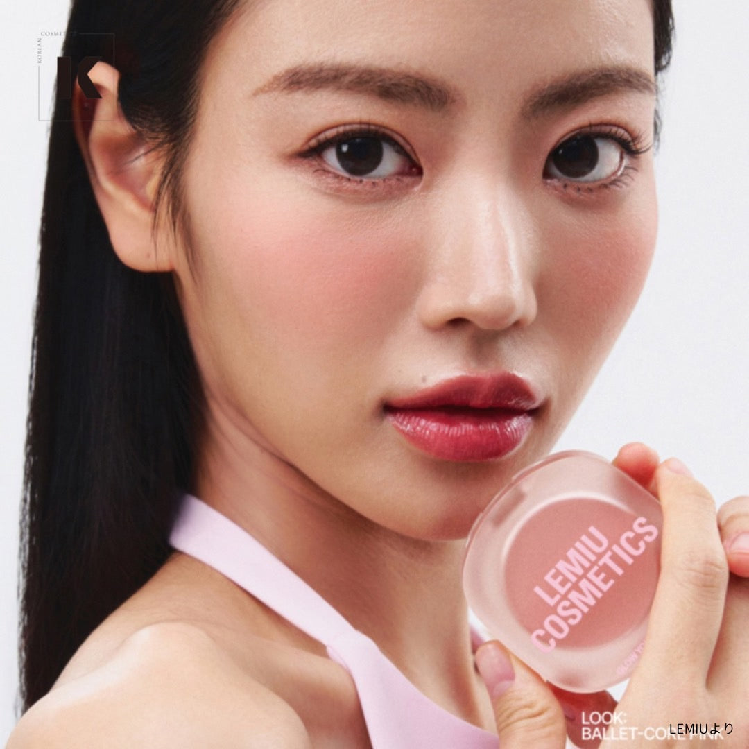 Woman holding LEMIU Eye To Cheek cosmetic product in hand, showcasing its vibrant pink color and texture for makeup application.