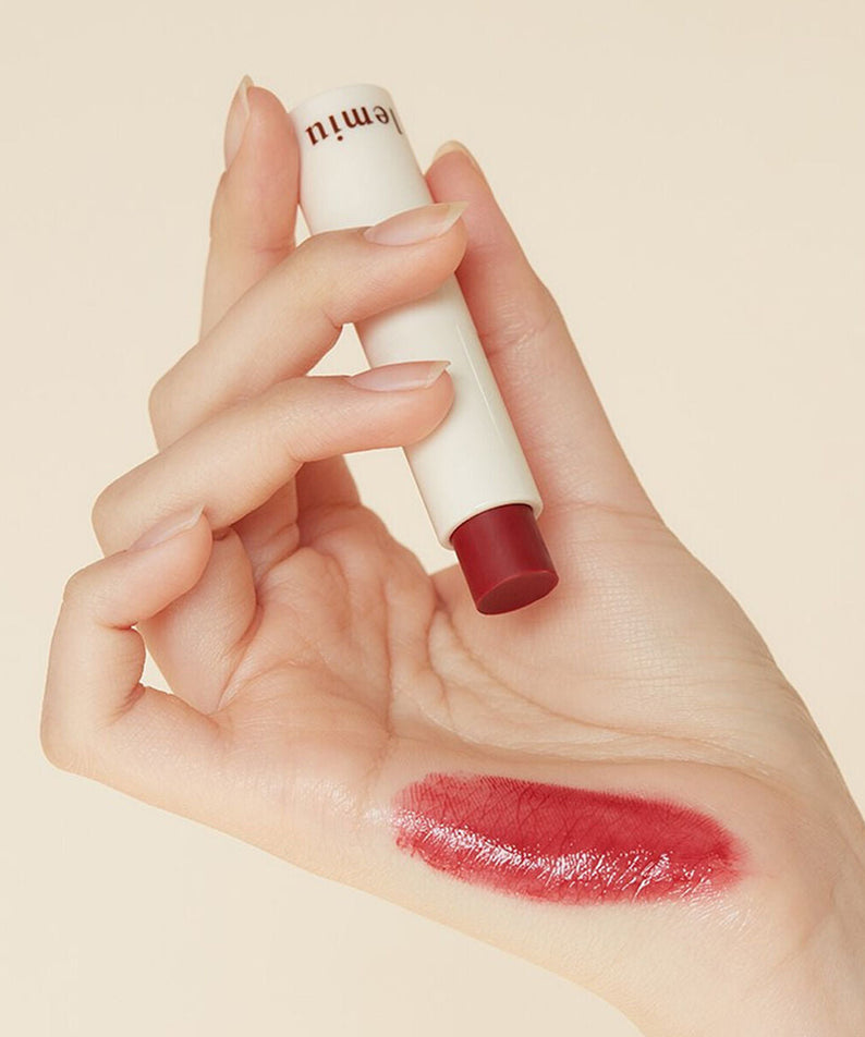 Hand holding LEMIU Sole Mood Vegan Lip Balm with swatch on skin.