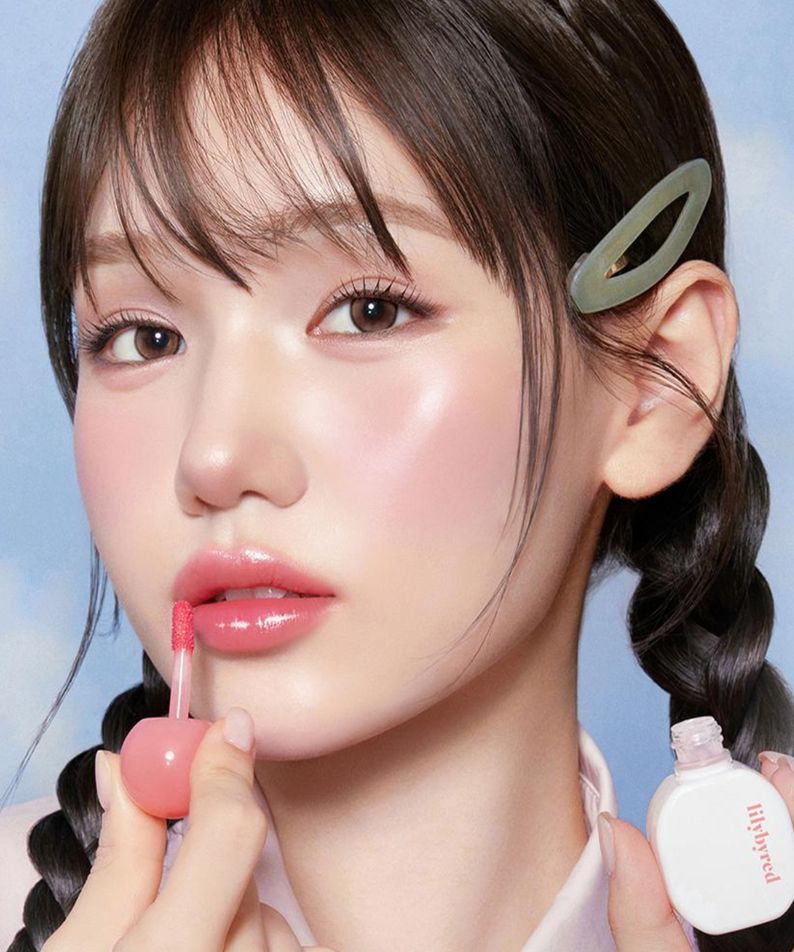 Model applying LILIBYRED Sugar Wrapping Tint Gloss for a glossy lip finish.