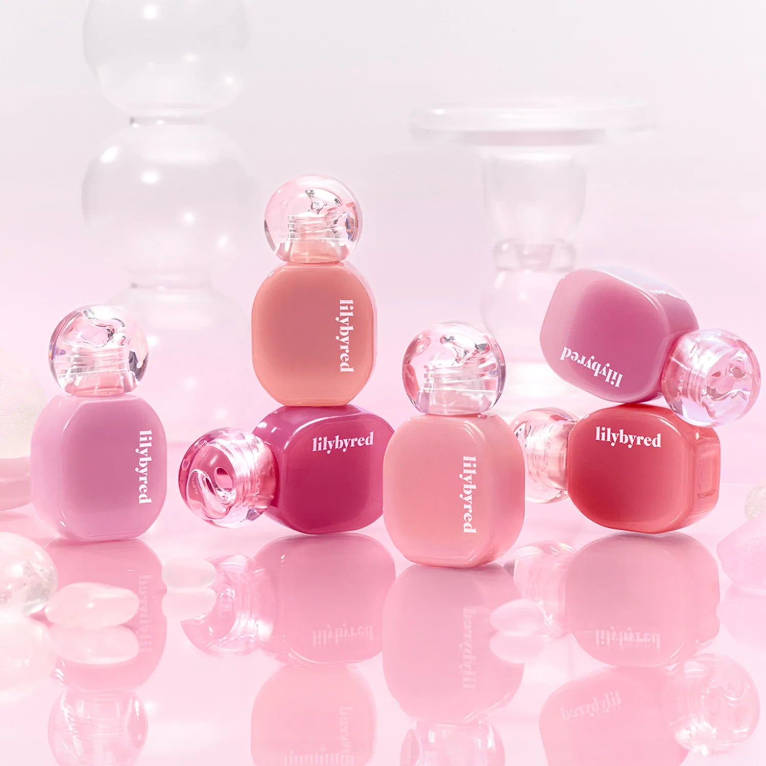 LILYBYRED Balming Dewy Tint bottles in various shades with pink background, showcasing vibrant lip tint options.