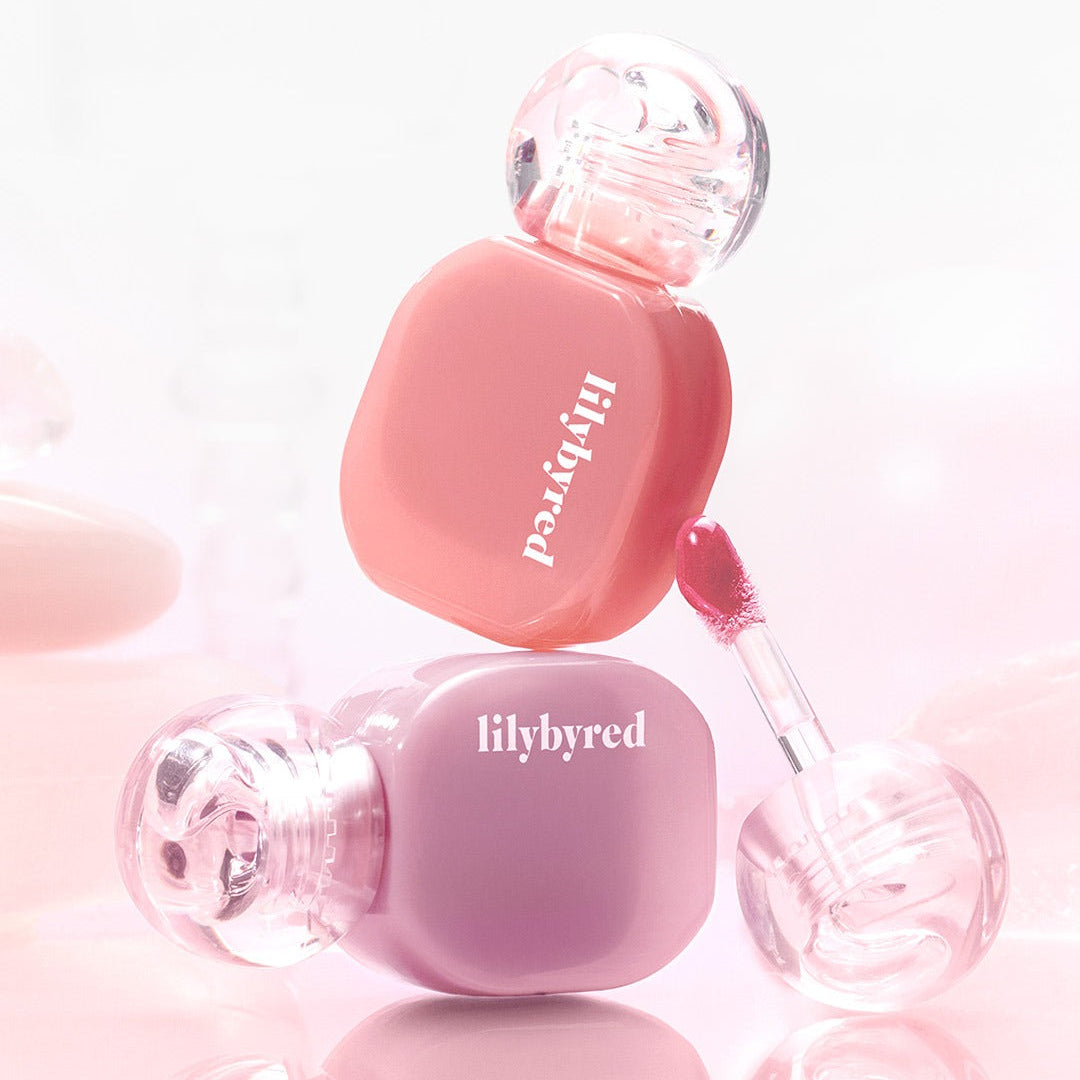 Two bottles of LILYBYRED Balming Dewy Tint in pink and purple shades with applicators, perfect for a glossy lip finish.