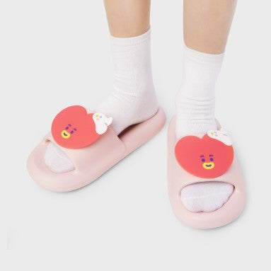 Child wearing LINE FRIENDS BT21 On The Cloud Edition Slippers with cartoon heart design on pink background.