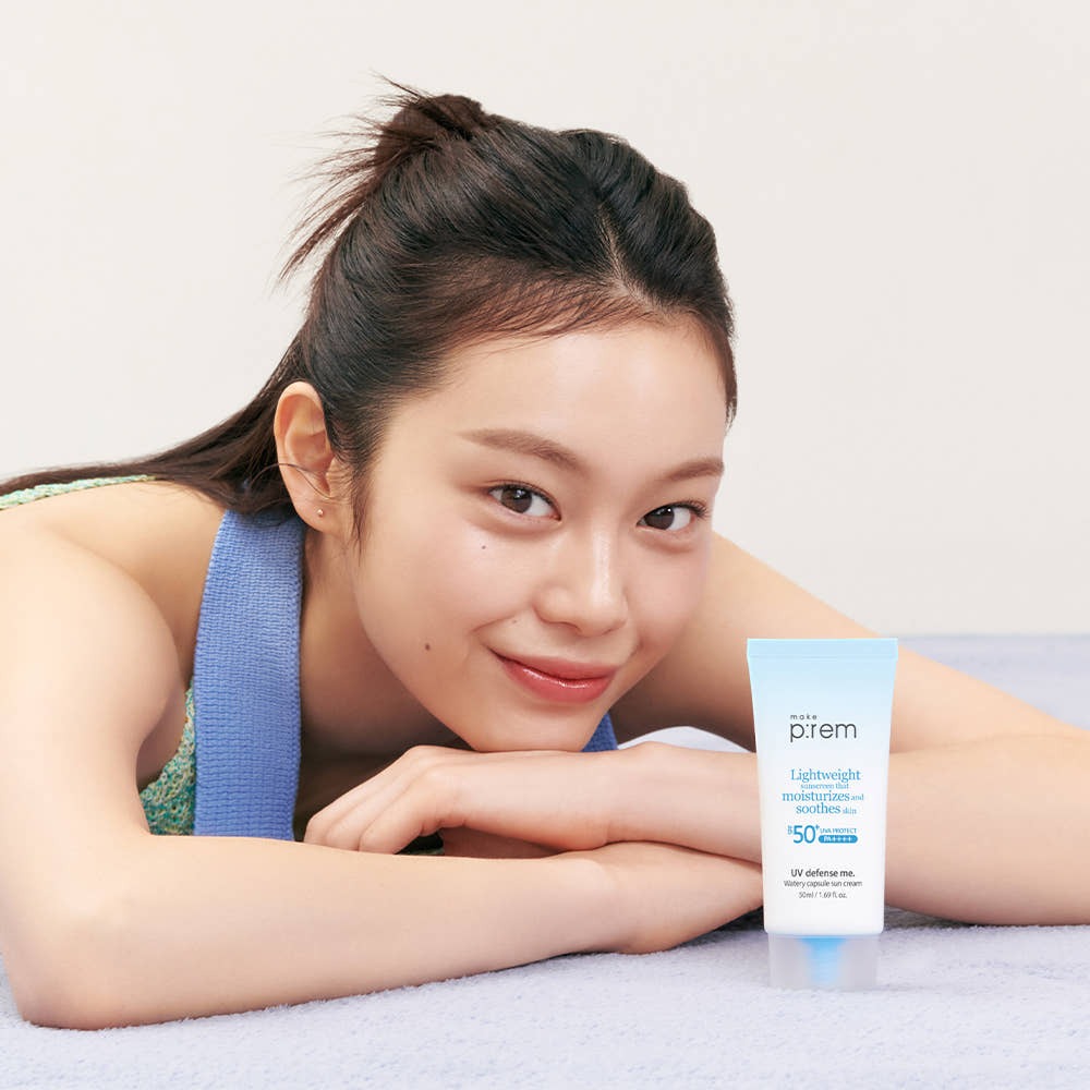 Woman with MAKE P:REM UV Defense Me Watery Capsule Sunscreen 50ml SPF50+ PA++++ smiling beside the product tube.