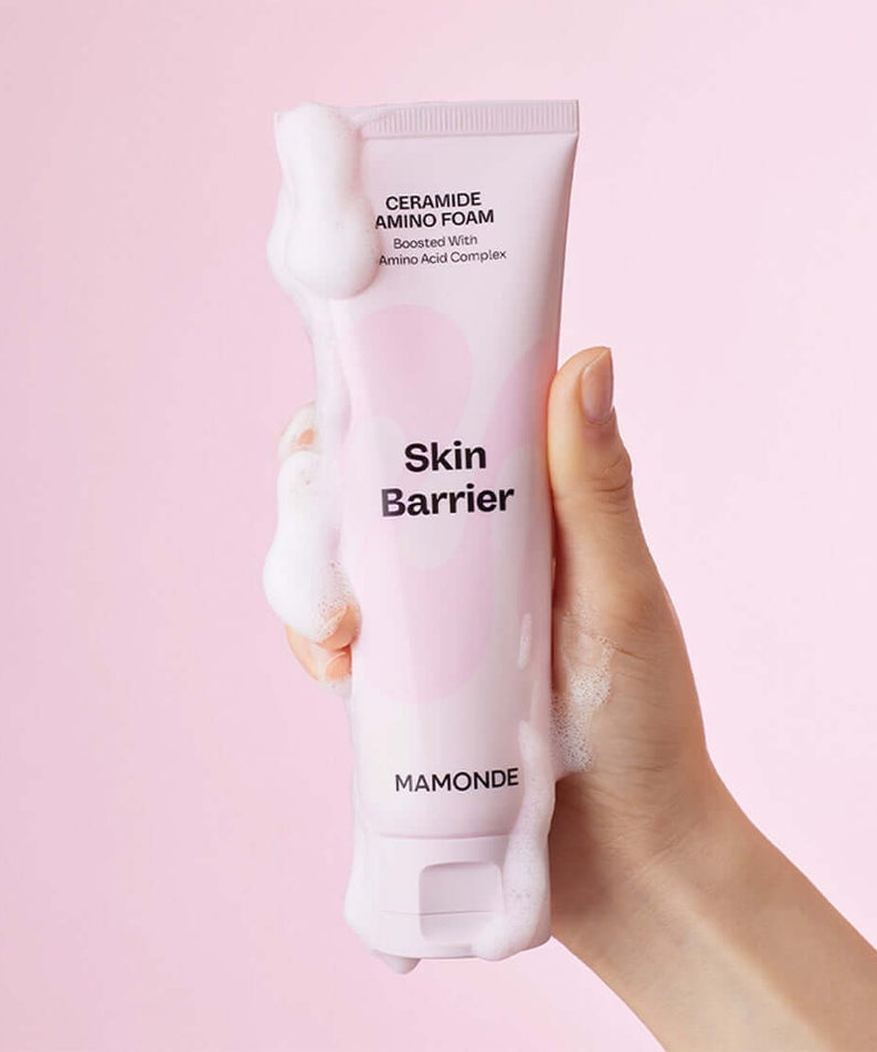 Hand holding MAMONDE Ceramide Amino Foam 120g with bubbles on pink background.