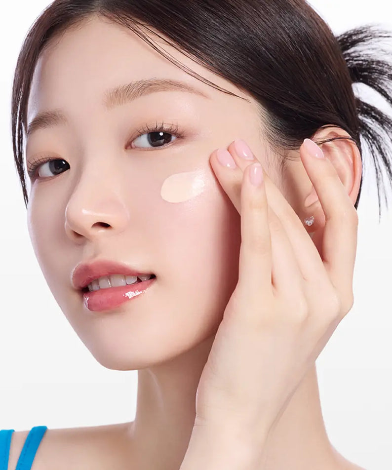 Woman applying MAMONDE NEW Floraglow Rose Tinted Sun Serum 35ml on her cheek to demonstrate skincare routine.