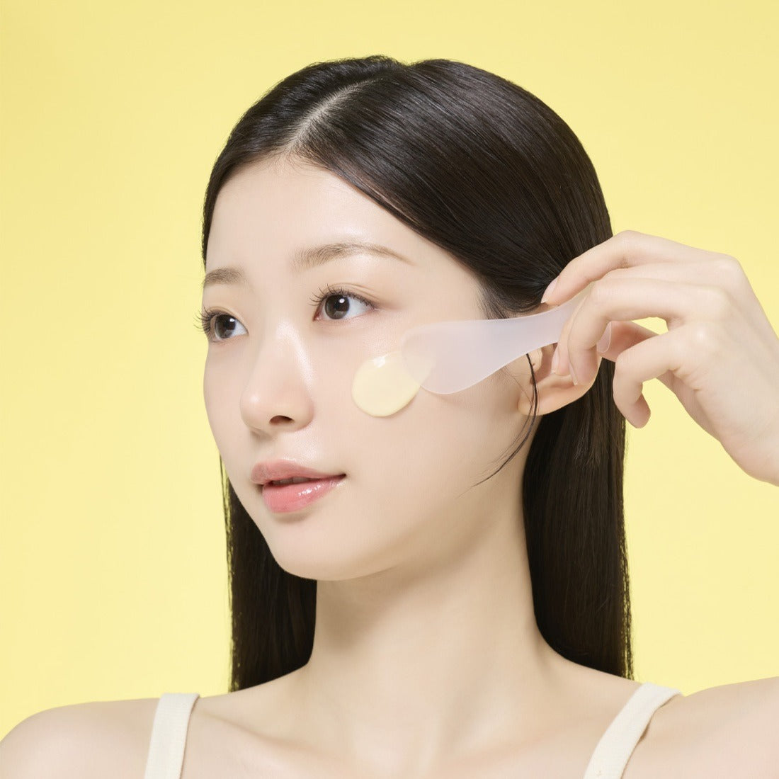 Woman applying MAMONDE Original Recipe Honey Modeling 1 Pack on face with spatula, skincare routine, yellow background
