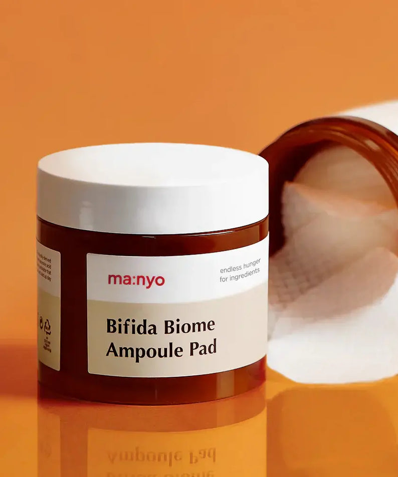 MANYO Bifida Biome Ampoule Pad 70 Sheets on an orange background with opened lid and visible cotton pads.
