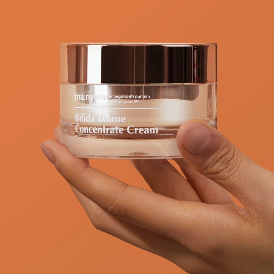 MA:NYO Bifida Biome Concentrate Cream 50ml in hand, showcasing the product packaging against an orange background.