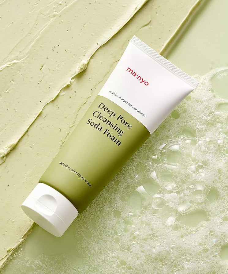 MANYO Deep Pore Cleansing Soda Foam 150ml tube lying on a textured green surface with bubbles around it