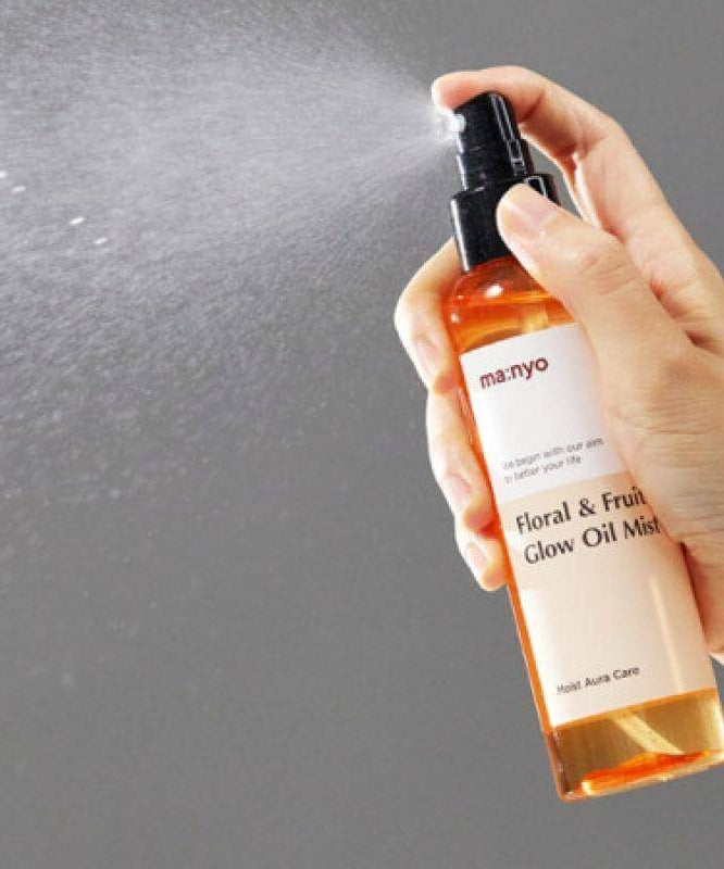 MANYO Floral & Fruit Glow Oil Mist 150ml being sprayed from a bottle, highlighting the product's hydrating qualities.