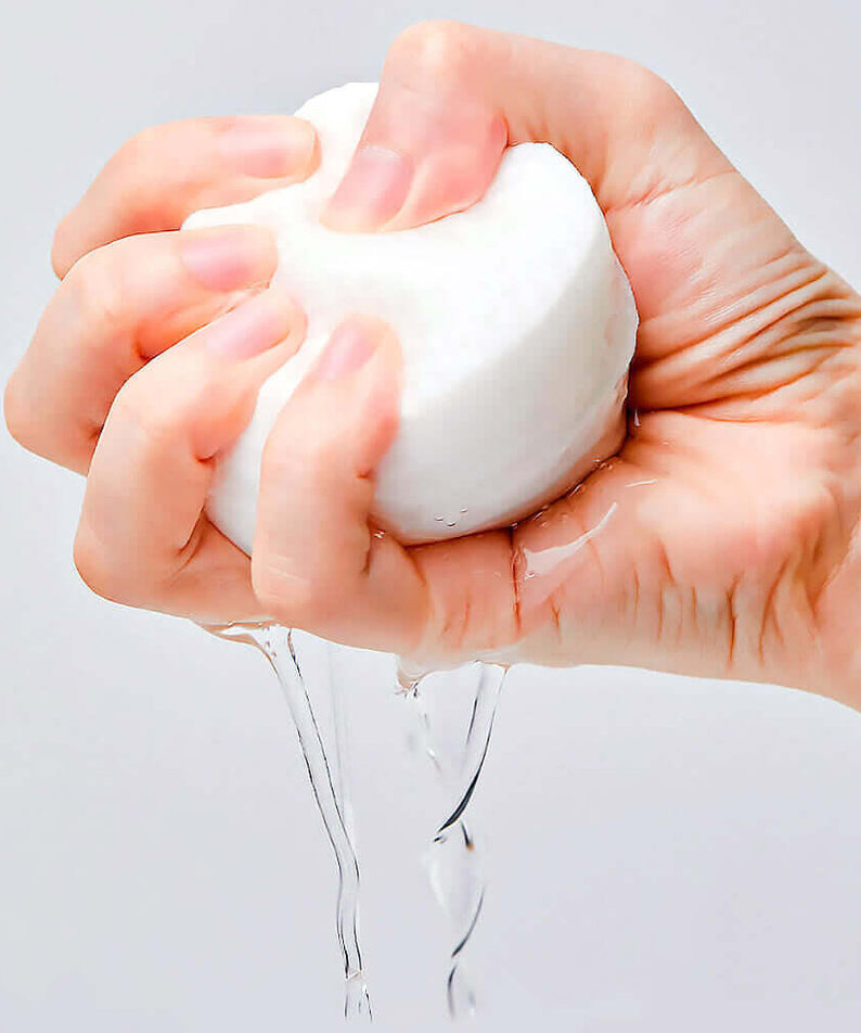 Hand squeezing a moist pad from MANYO Galactomy Clear Skin Pads 60 sheets, showcasing its effective hydrating properties.