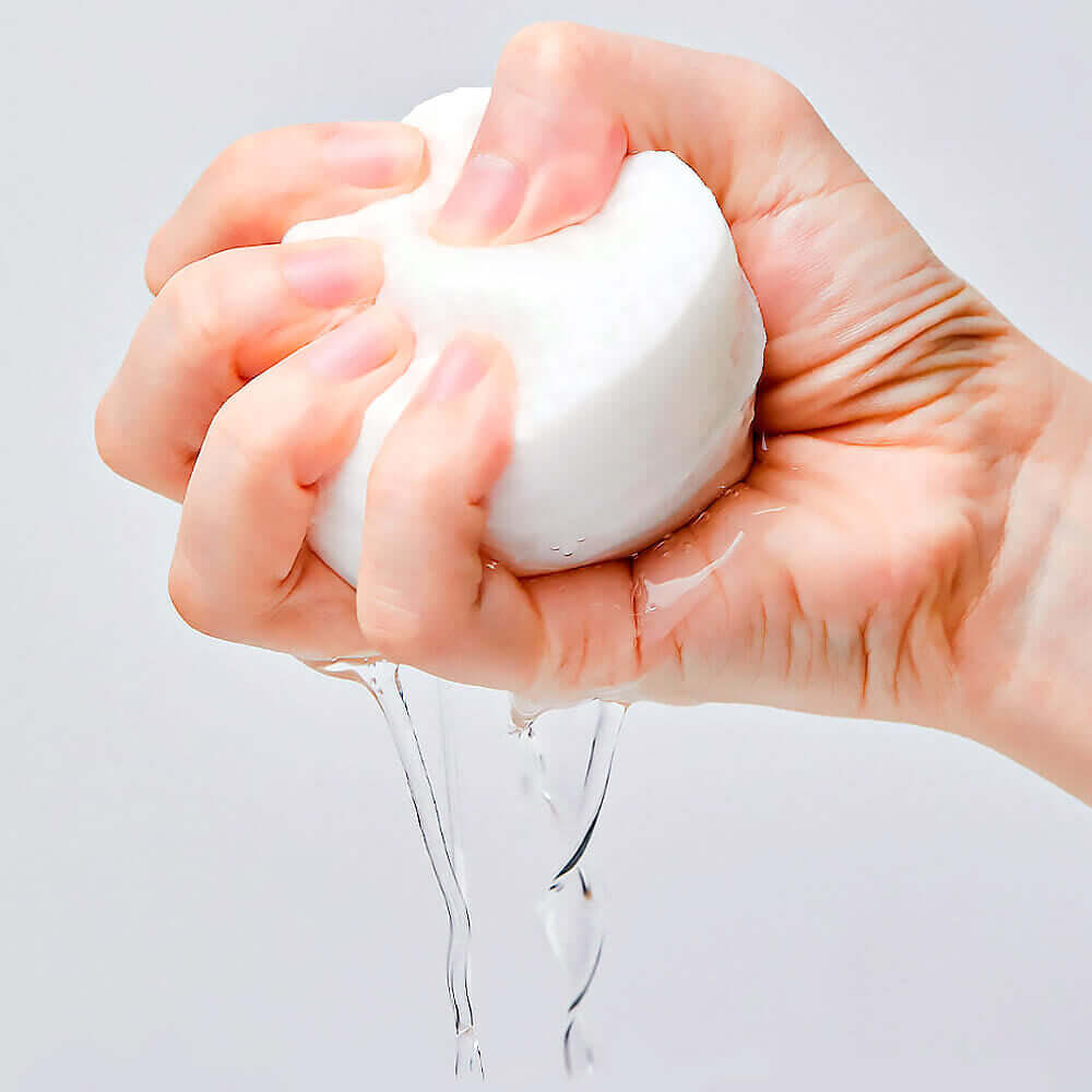 Hand squeezing a moist pad from MANYO Galactomy Clear Skin Pads 60 sheets, showcasing its effective hydrating properties.