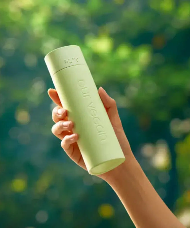 Person holding MANYO Our Vegan Heartleaf Moisture Soothing Toner 315ml against a green background