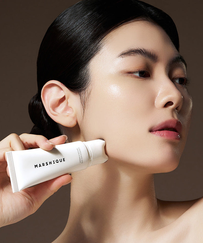 Woman using MARSHIQUE Wrinkle Repair Guasha Essence 45ml for skincare routine.