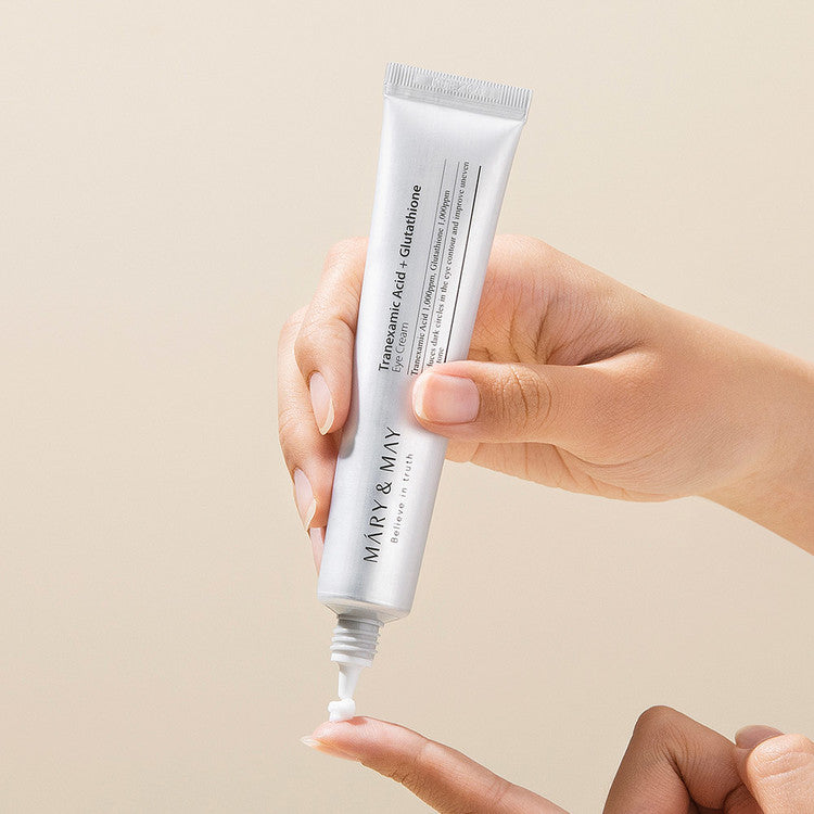 Hand holding tube of MARY&MAY Tranexamic Acid Glutathione Eye Cream 30ml