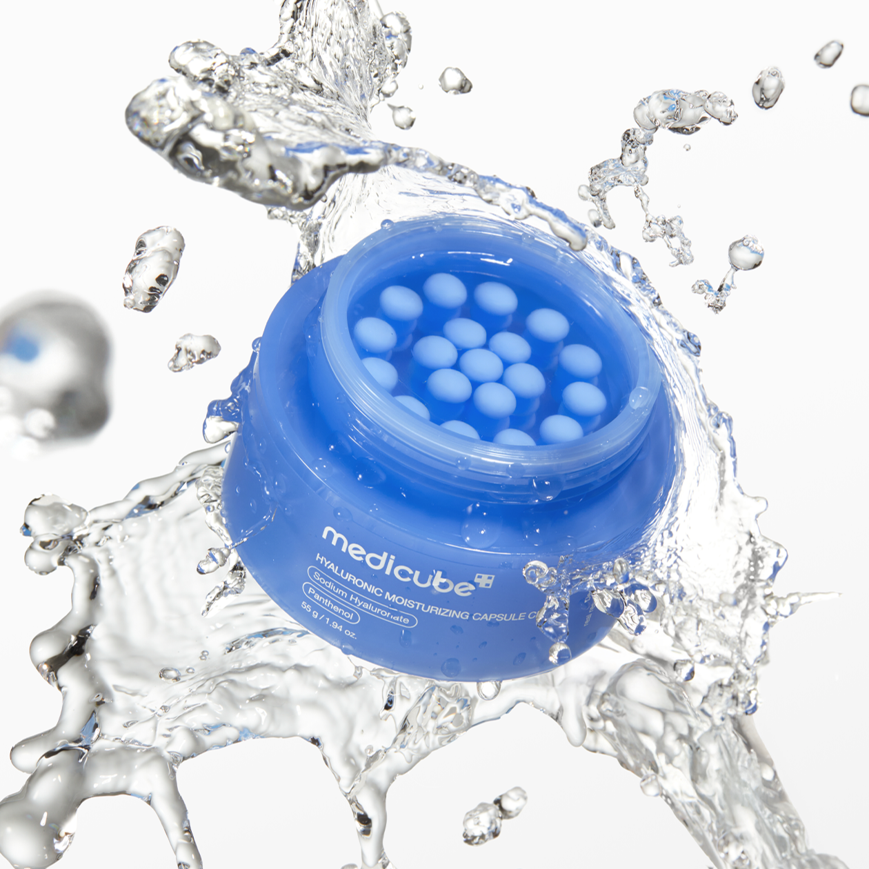 MEDICUBE Hyaluronic Moisturizing Capsule Cream 55g in a blue jar with water splash, showcasing texture and hydrating properties.
