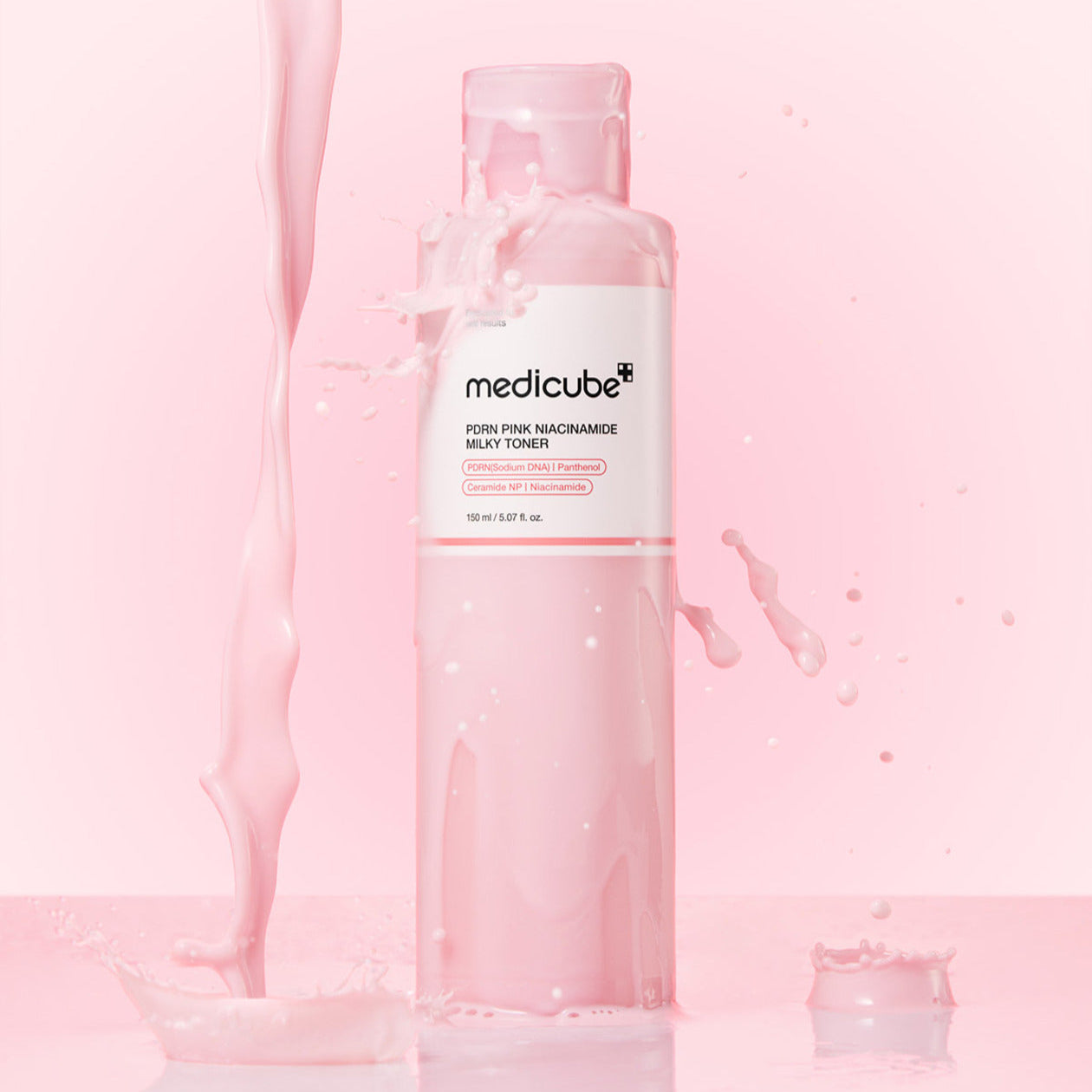 Bottle of MEDICUBE PDRN Milky Toner Essence 150ml with pink liquid splash on a pink background