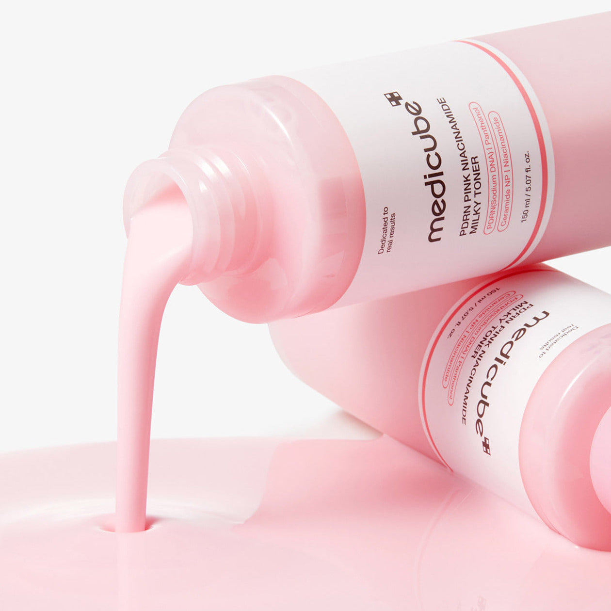 MEDICUBE PDRN Milky Toner Essence 150ml pouring from the bottle, showcasing the texture and color of the skincare product.