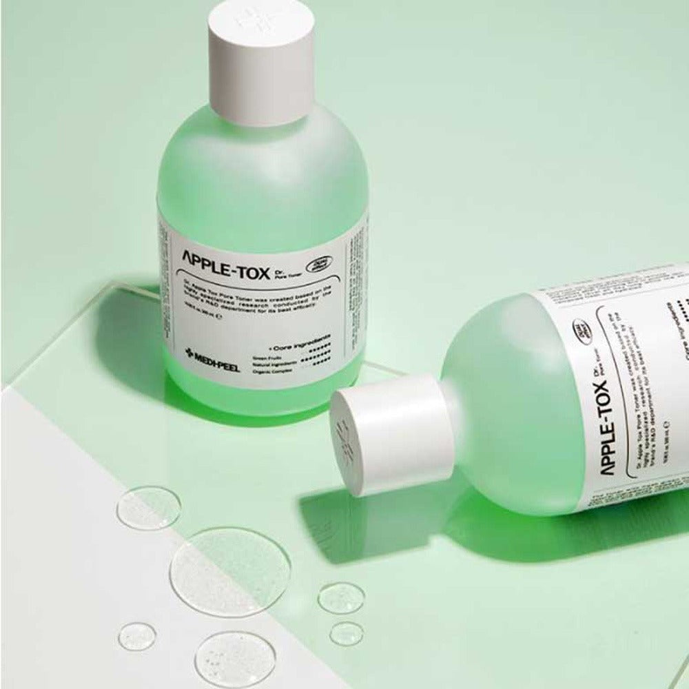 Two bottles of MEDIPEEL Dr.Apple Tox Pore Toner 500ml on a green background with liquid droplets.