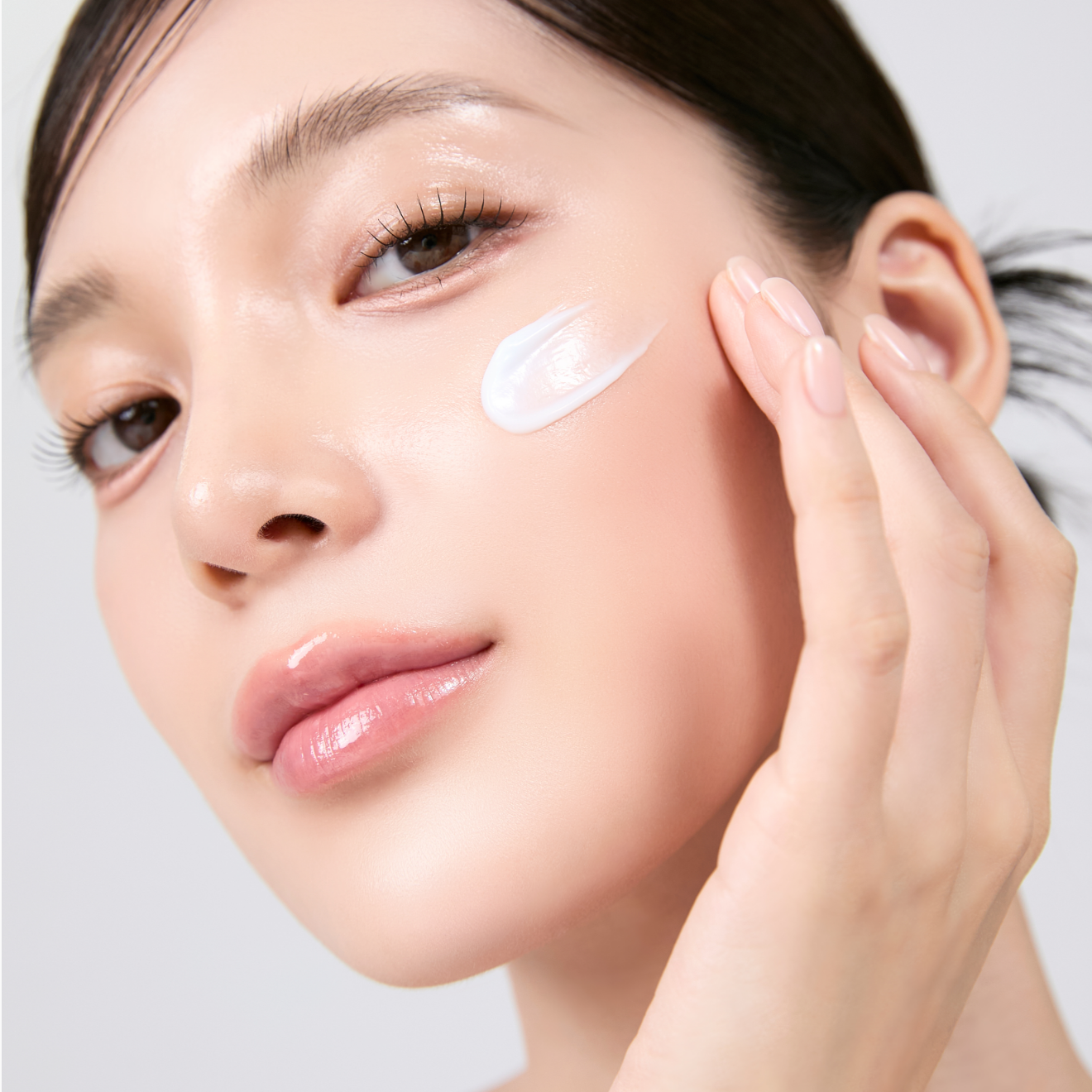 Woman applying MEDITHERAPY Squalane Skin Booster Moisturizer 150ml on cheek for radiant skin care