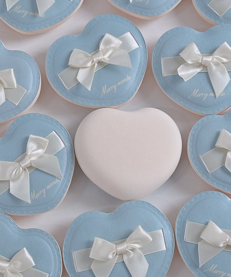 Heart-shaped packaging of MERRY MONDE Merry Everyday Color Correcting Concealer with elegant bows and pastel colors.