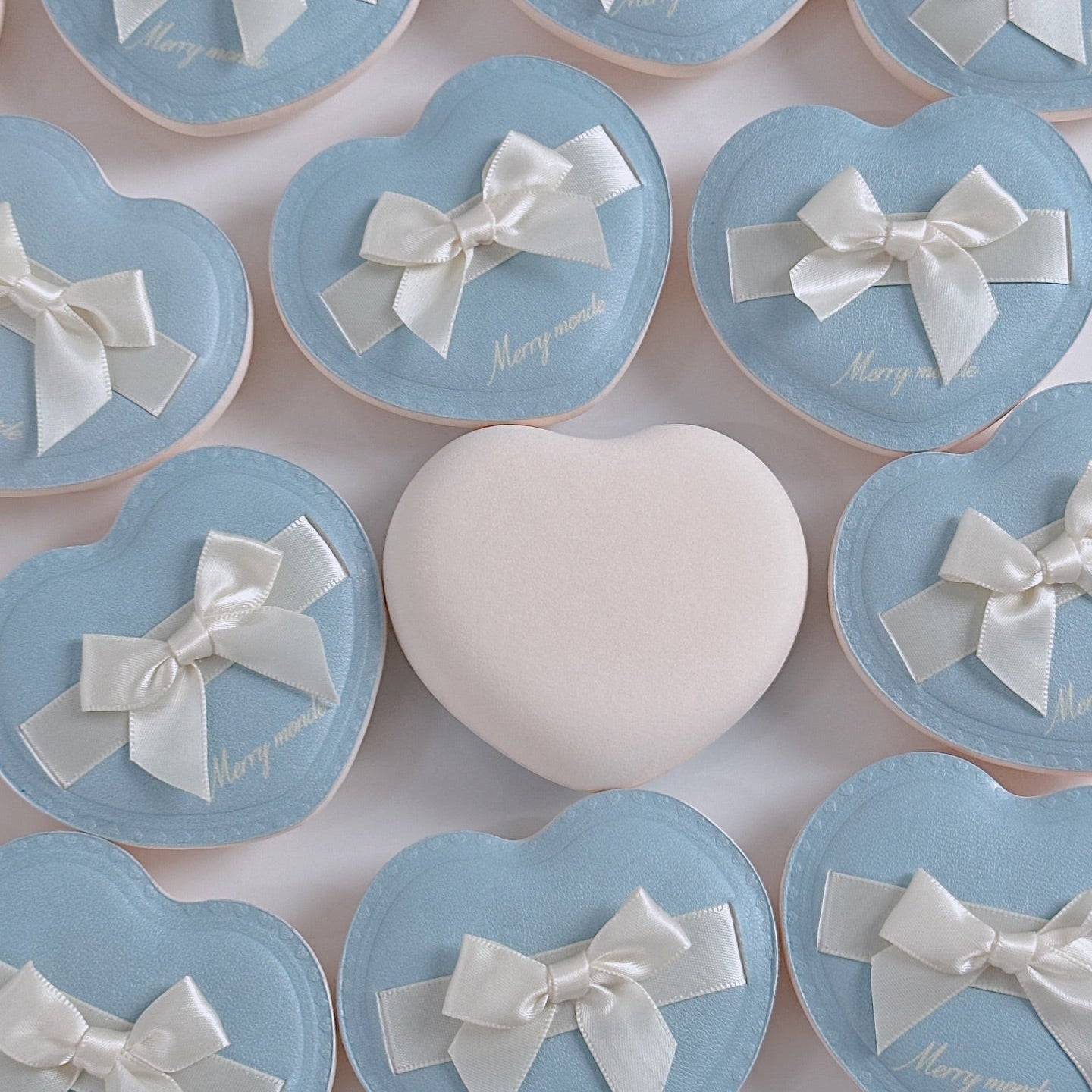 Heart-shaped packaging of MERRY MONDE Merry Everyday Color Correcting Concealer with elegant bows and pastel colors.