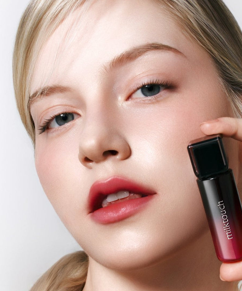 Model holding MILK TOUCH Black Peel-Off Lip Tattoo showing red lip color effect.