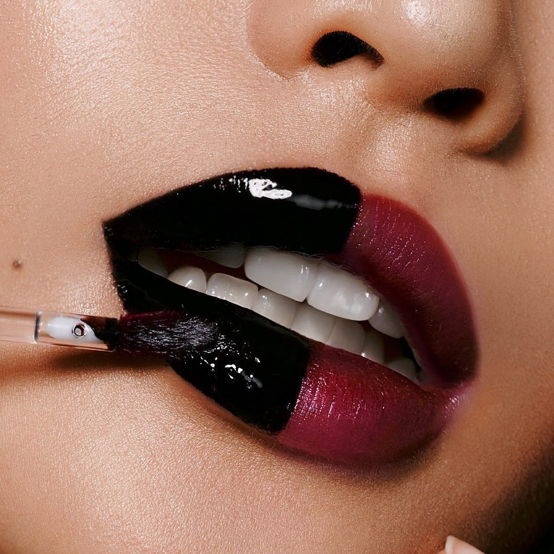 Close-up of person applying MILK TOUCH Black Peel-Off Lip Tattoo with brush, showcasing glossy texture and vivid color transformation.