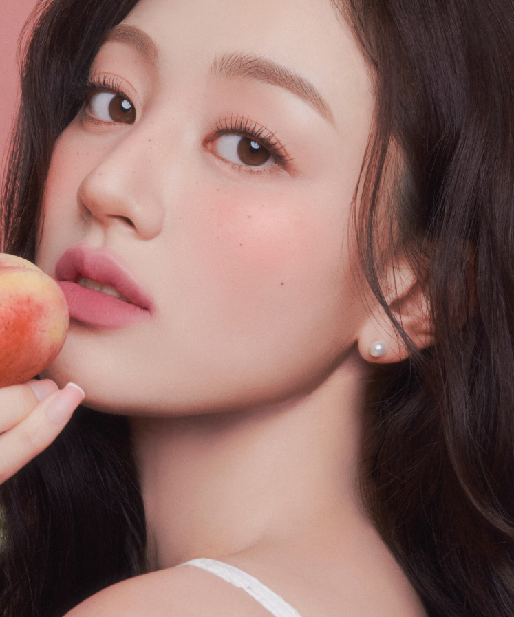 Woman holding a peach, showcasing the smooth finish of MILK TOUCH Spread Fit Blur Tint on her skin.