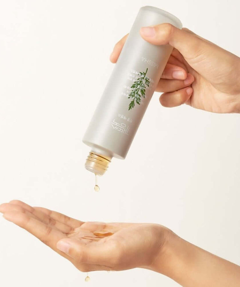 Person pouring MISSHA Artemisia Soothing Essence 150ml into hand, highlighting its texture and soothing benefits.