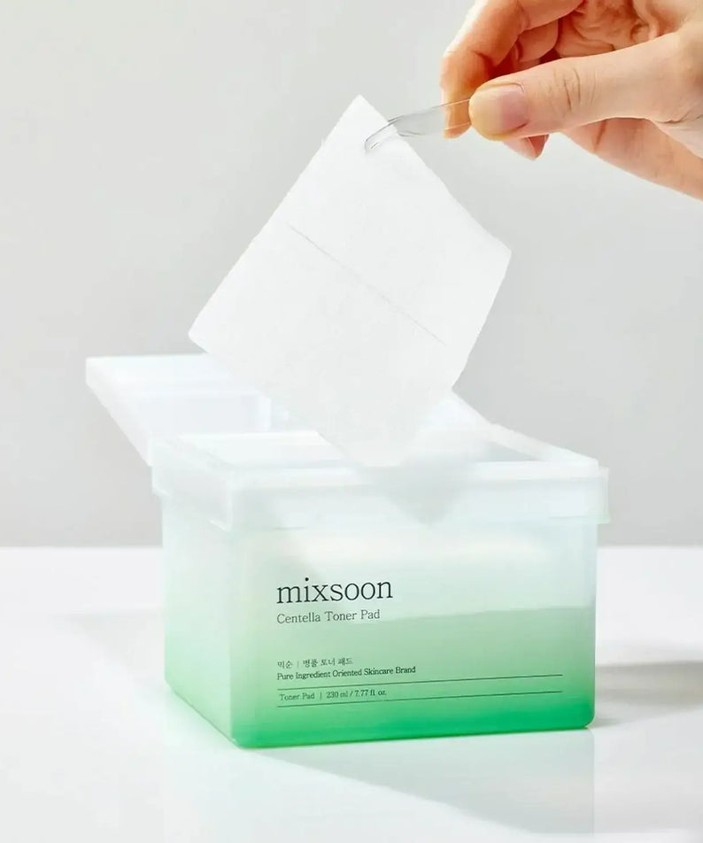 Hand holding MIXSOON Bottle Grass Toner Pad above open box.