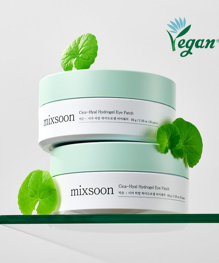 MIXSOON Cica Hyal Hydrogel Eye Patch 60 Sheets on display with green leaves on a glass surface, featuring vegan certification.
