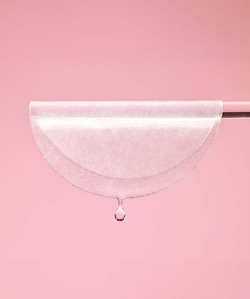 Close-up of MIXSOON Collagen Toner Pad with drop against a pink background, highlighting its hydrating properties.