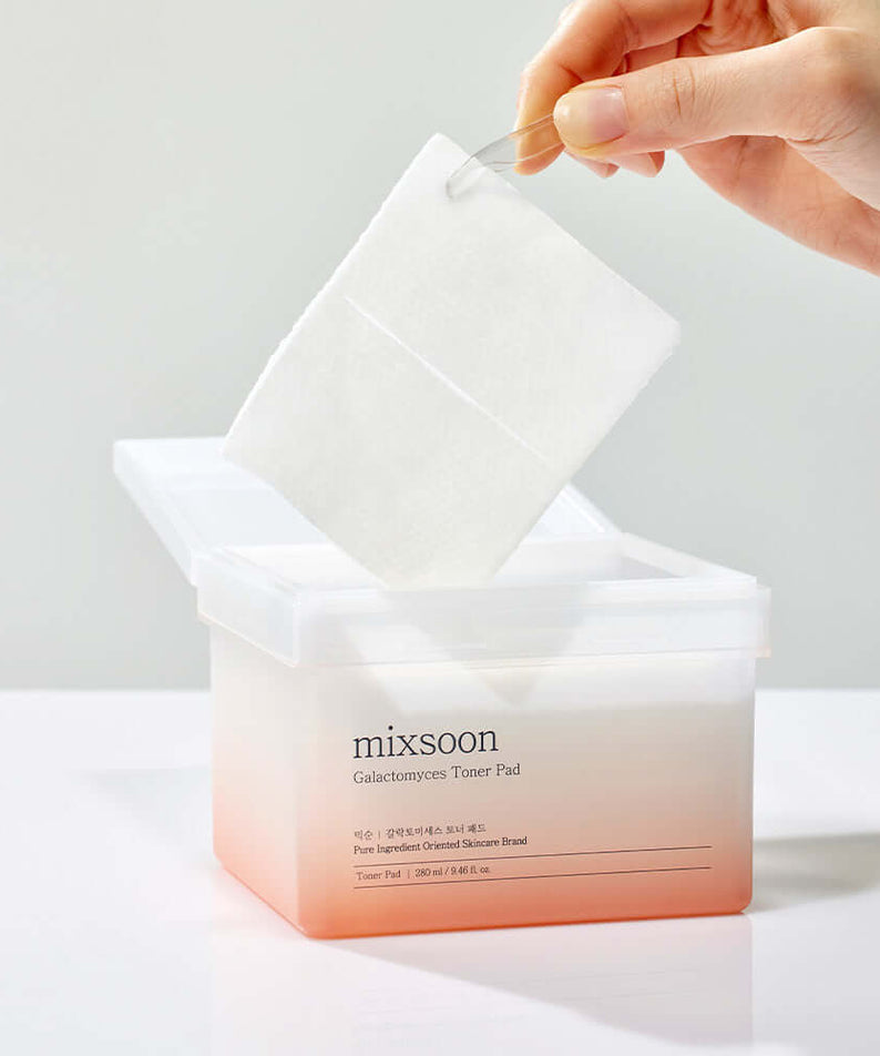 MIXSOON Galactomyces Toner Pad in use, showing a pad being removed from the container for skincare application.