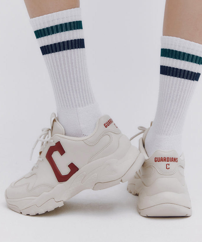 Person wearing MLB Bigball CHUNKY Window Cleaveland Gardians sneakers with striped socks, showcasing sports footwear design.