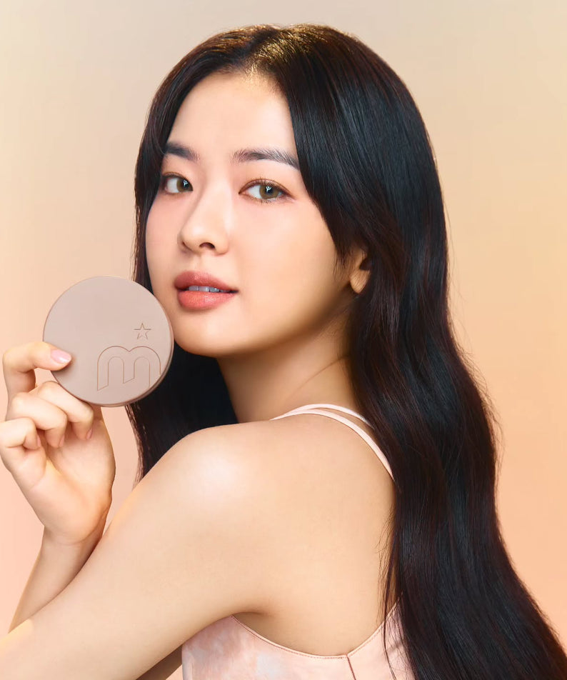 Woman holding MOONSHOT Conscious Fit Cushion Foundation with soft focus background.