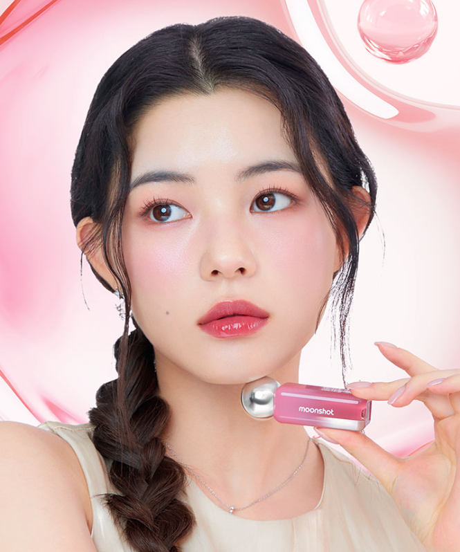 Model holding MOONSHOT Jelly Moon Glow Tint with pink glossy background showing vibrant lip color.