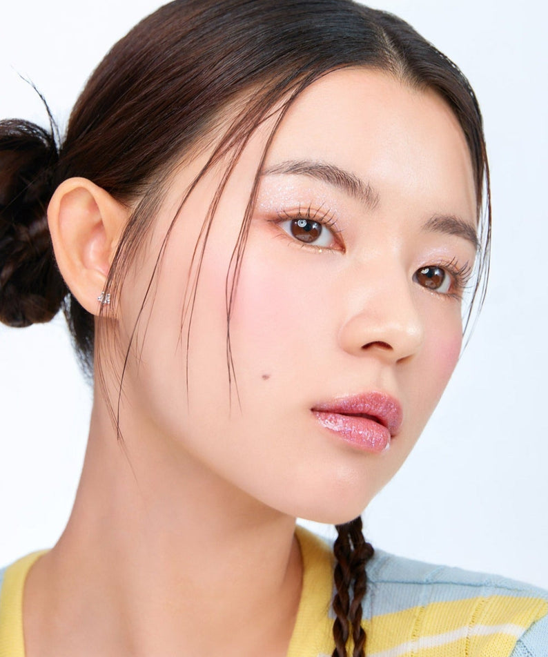 Model showcasing MOONSHOT Melting Mood Lip & Cheek in natural light, highlighting smooth texture and vibrant color on lips and cheeks.