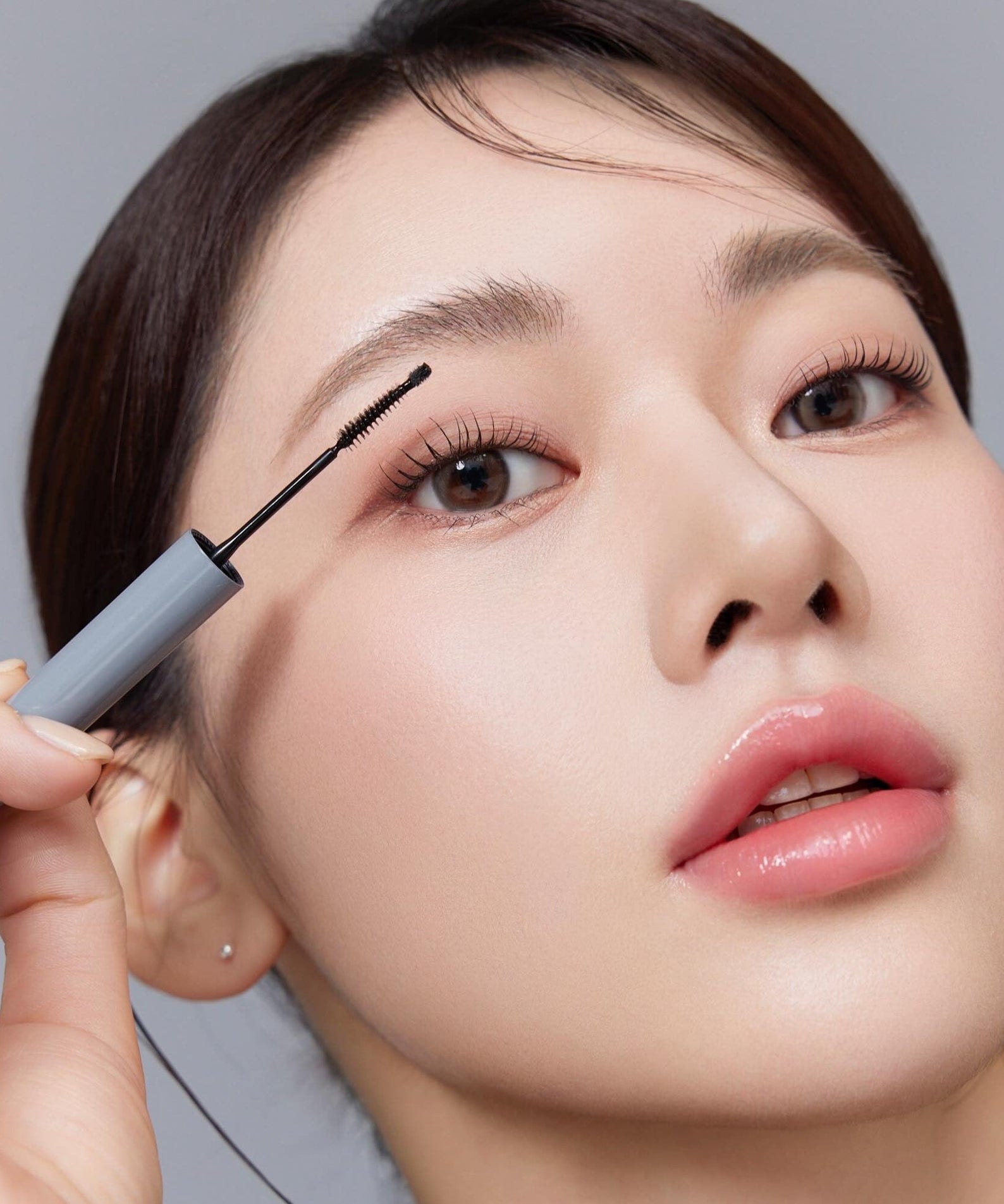 Close-up of a model applying mascara with precision, showcasing long lashes and smooth skin for beauty and makeup inspiration.