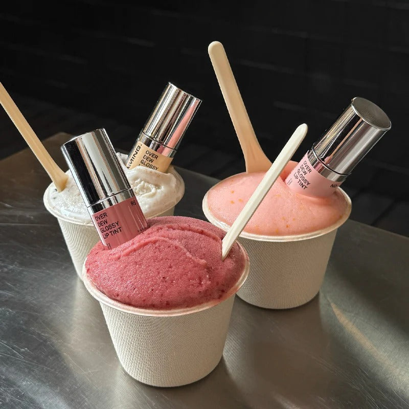 NAMING Overdew Glossy Lip Tint displayed with colorful gelato cups as a creative product presentation