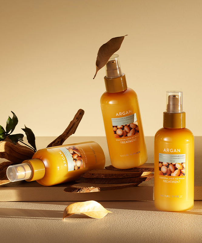 Image of NATURE REPUBLIC Argan Essential Hair No Wash Treatment 160ml bottles with natural decor on a beige surface.