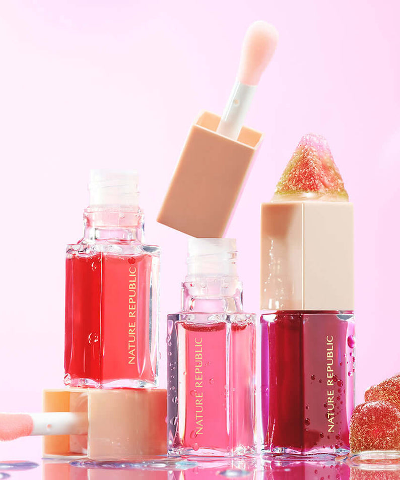 NATURE REPUBLIC Glaze Shine Lip Oil in various shades with applicators on pink background.
