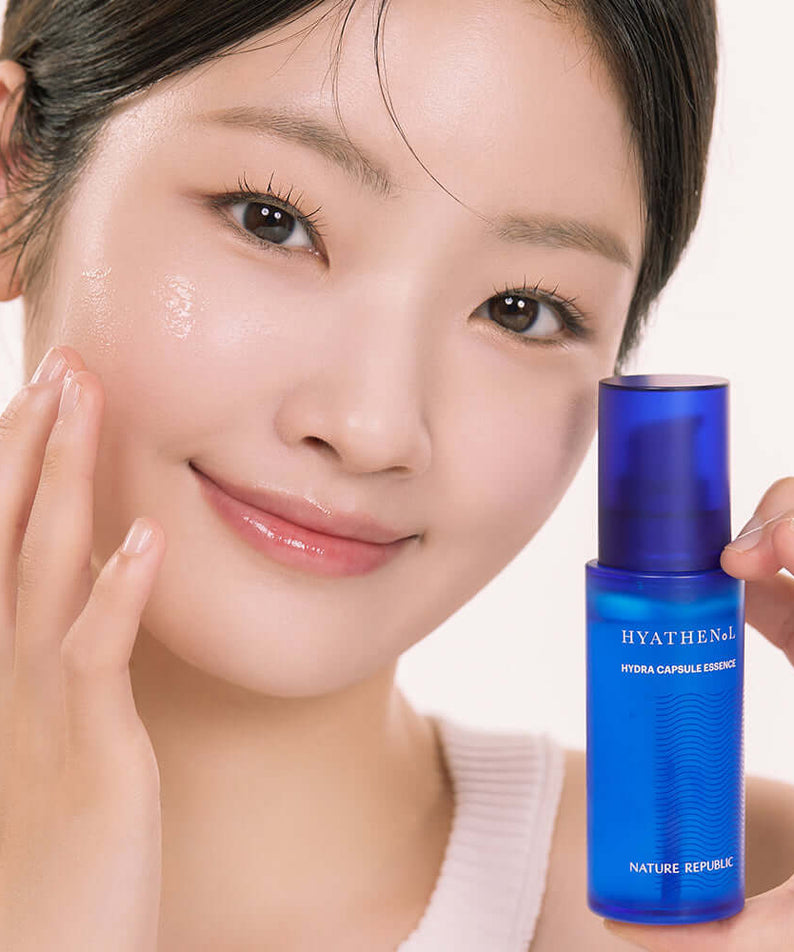 Young woman applying NATURE REPUBLIC Hyathenol Hydra Capsule Essence 50ml for glowing skin.