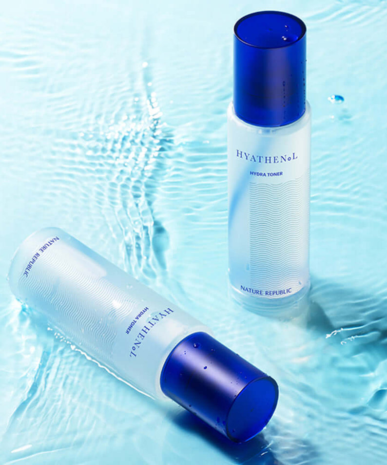 Two bottles of NATURE REPUBLIC Hyathenol Hydra Toner 150ml placed on a blue watery surface.
