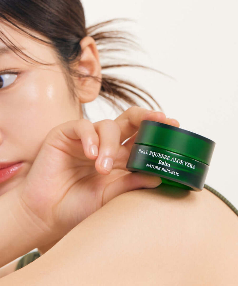 Person holding NATURE REPUBLIC Real Squeeze ALoe Vera Balm 25g jar on shoulder
