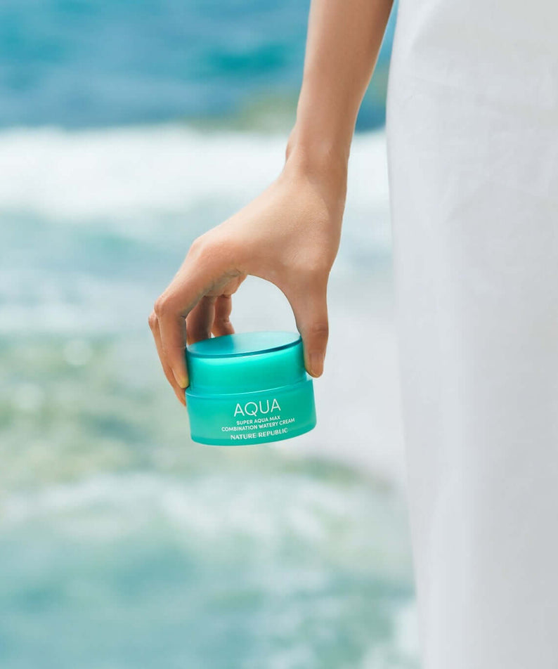 NATURE REPUBLIC Super Aqua Max Combination Moisture Cream 80ml held by hand near ocean backdrop